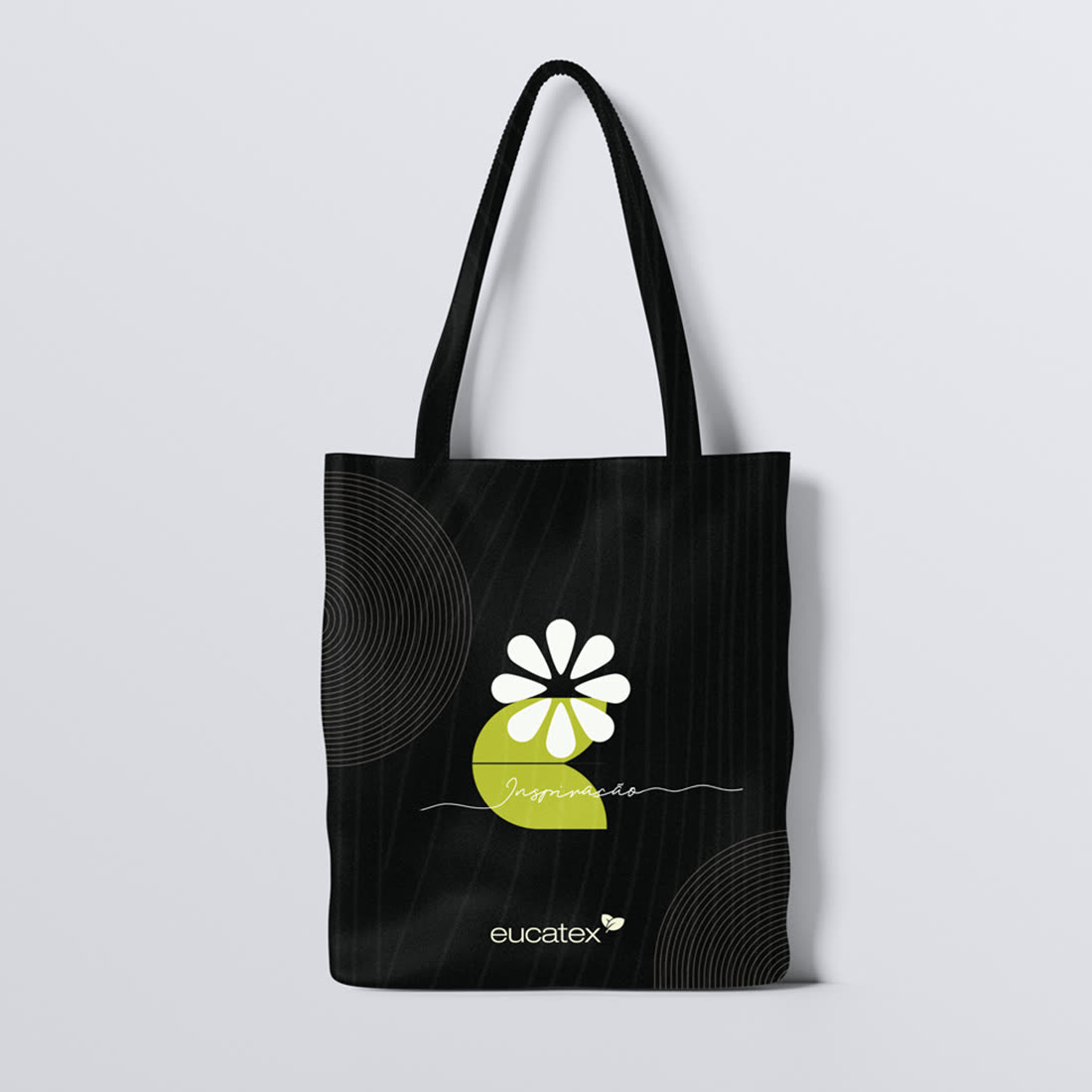 Ecobag preta da Eucatex pendurada, com a flor branca sobre meia-lua verde e a assinatura Inspiração.