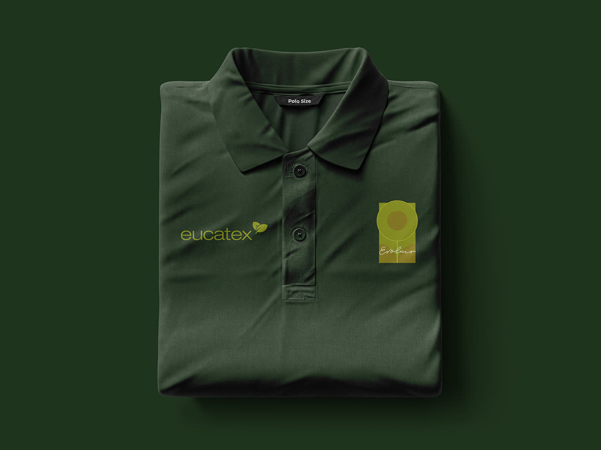 Camisa polo verde-escura dobrada e vista de cima, com o logotipo eucatex e o selo Evoluir.