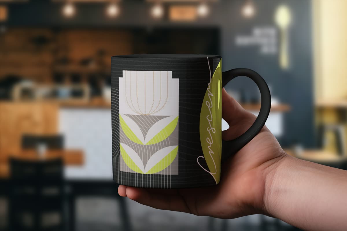 Mão segurando a caneca preta com o motivo floral e a assinatura Crescer, em cafeteria desfocada.