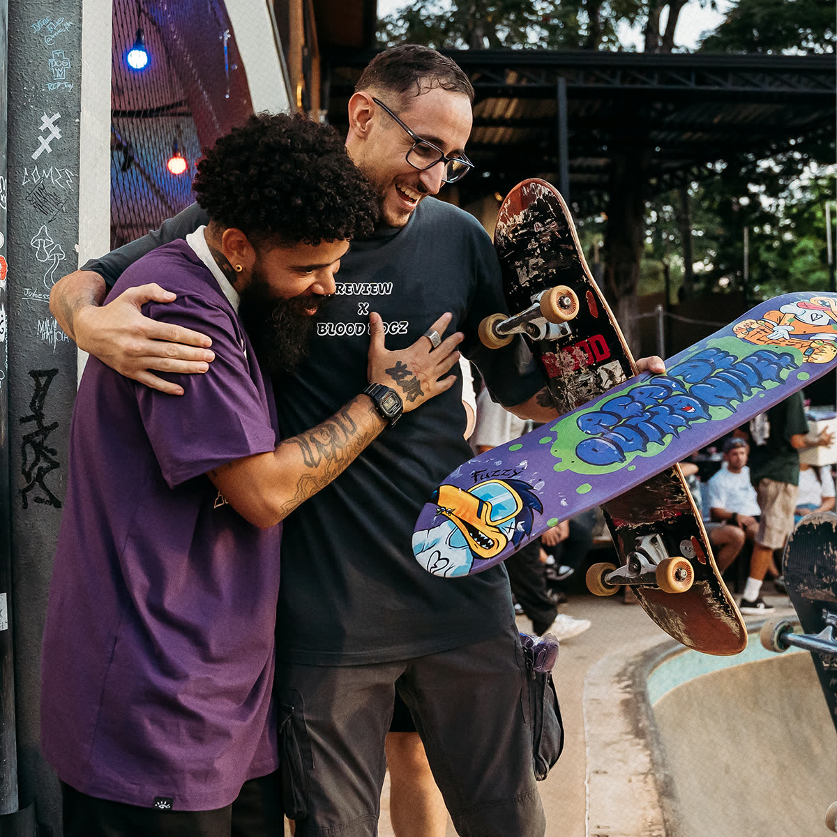 Registro do campeonato de melhor manobra, com dois participantes se abraçando e o shape estampado.