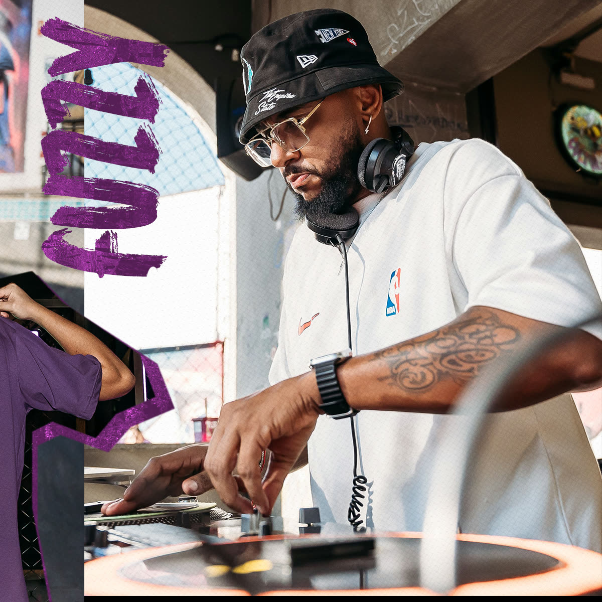 DJ tocando na pista durante o evento, com o lettering do Fuzzy em roxo.